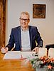 Der Oberbürgermeister der Stadt Forchheim an einem Schreibtisch mit einem Adventsgesteck im Vordergrund
