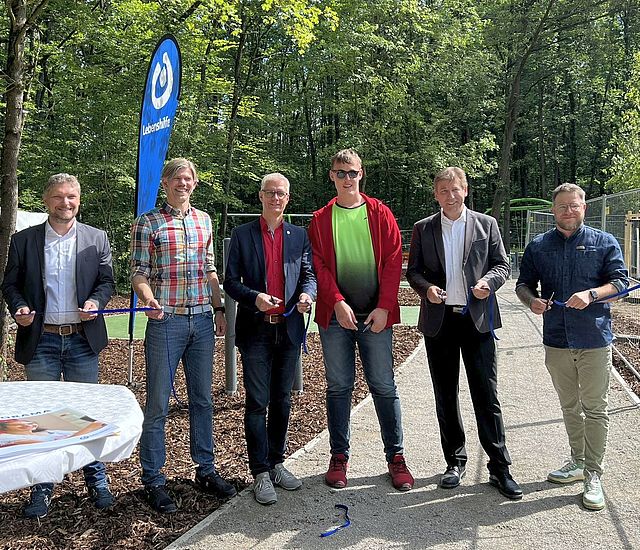 Ein Band zur Einweihung des Spielplatzes wird zerschnitten.