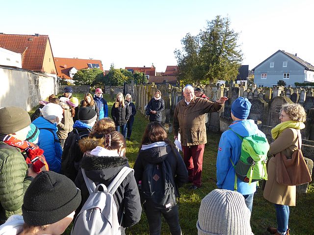 Rolf Kießling, Historiker, mit Schüler*innen auf dem jüdischen Friedhof.