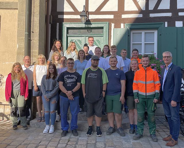 Eine Gruppe junger Menschen steht vor einem Fachwerkgebäude.