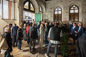 Zahlreiche Gäste versammeln sich zur symbolischen Grundsteinlegung in der großen Rathaushalle, die aktuell eine Großbaustelle ist.