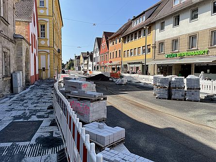 Eine Baustelle entlang einer Straße in der Stadt. Sie Gehwege und die STraße sind durch Absperrungen getrennt.