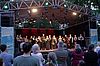 Konzert des KulturSommerQuartiers in Forchheim. Auf einer Bühne steht das Ensemble des Symphony Orchestra mit Blumensträußen in den Händen.