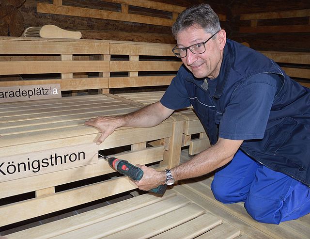 Ewald Hack vom städtischen Bauhof montiert die Platzschilder in der Event-Sauna.