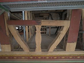 Man sieht einen Ausschnitt einer Fachwerk-Außenfassade. Das Mauerwerk wurde entfernt. Teilweise ist das alte und beschädigte Holz im Fachwerk erneuert worden. Die das Fachwerk sieht man in den Innenraum eines Gebäudes.