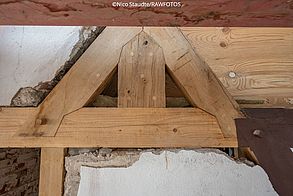 Eine Detailaufnahme zeigt ausgebesserte Holzelemente an einem Fachwerk.