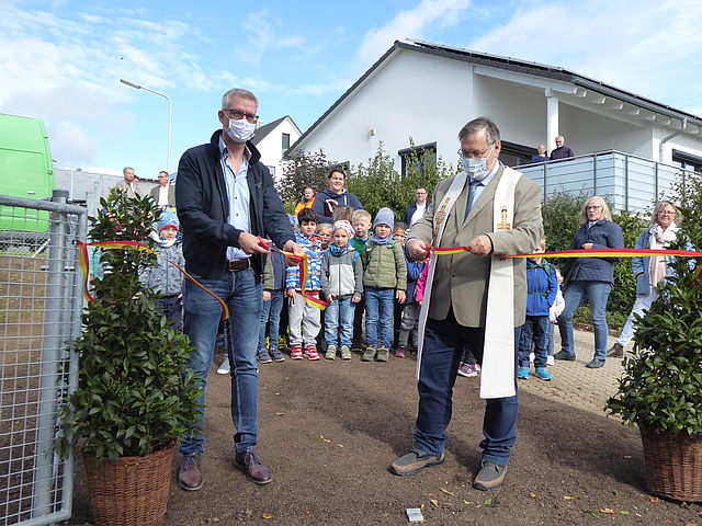Oberbürgermeister Dr. Kirschstein und Pater Bernhard Kuhn (rechts) durchschneiden das Band.