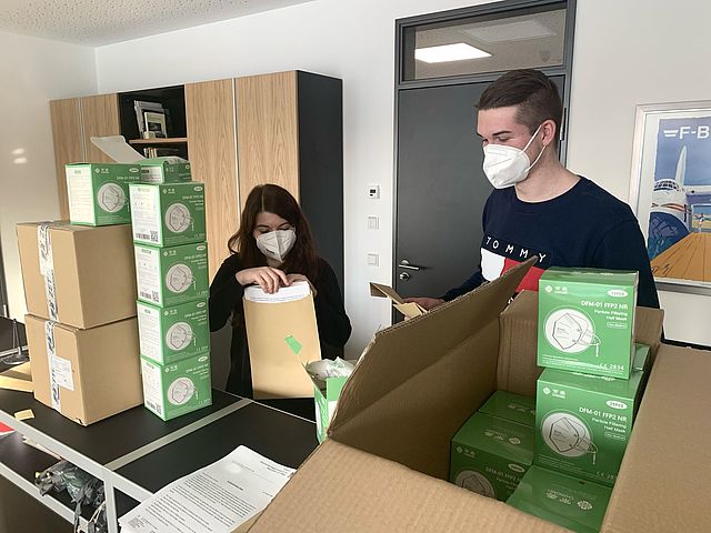 Frau und Mann verpacken Masken in Kartons