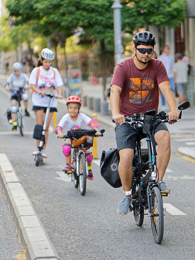 Hintereinander fährt eine Familie auf einem Radweg.