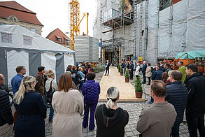 Ein Mann hält vor einer Menschenmenge eine Ansprache auf einer Großbaustelle.