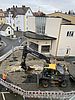 Aus der Vogelperspektive ist die Baustelle in der Wallstraße zu sehen. Ein Bagger entfernt die obere Straßendecke. Das Areal ist mit rot-weißen Bauzäunen abgesperrt.