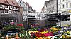 Ein Marktstand mit Frühlingsblühern an einem großen Stadtplatz..