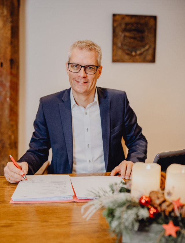 Der Oberbürgermeister der Stadt Forchheim an einem Schreibtisch mit einem Adventsgesteck im Vordergrund